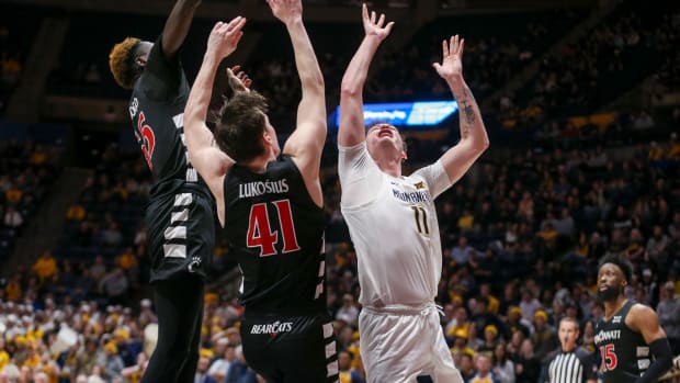 Jan 31, 2024; Morgantown, West Virginia, USA; West Virginia Mountaineers forward Quinn Slazinski (11) shoots against Cincinnati Bearcats forward Aziz Bandaogo (55) and Cincinnati Bearcats guard Simas Lukosius (41) during the second half at WVU Coliseum. Mandatory Credit: Ben Queen-USA TODAY Sports